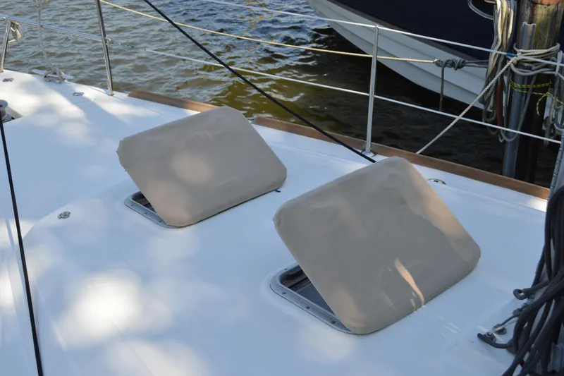 Slide: The Image of Beneteau Oceanis 34 sailboat deck with covered hatches, 2012 model, docked by water. - 26