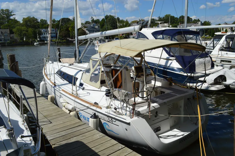 Slide: The Image of 2012 Beneteau Oceanis 34 sailboat docked at a marina, featuring a beige canopy. - 5