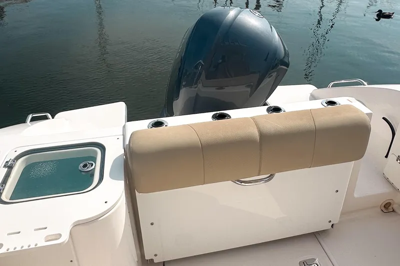 Slide: The Image of 2016 Pursuit C 238 Center Console boat with engine and seating, docked on calm water. - 6