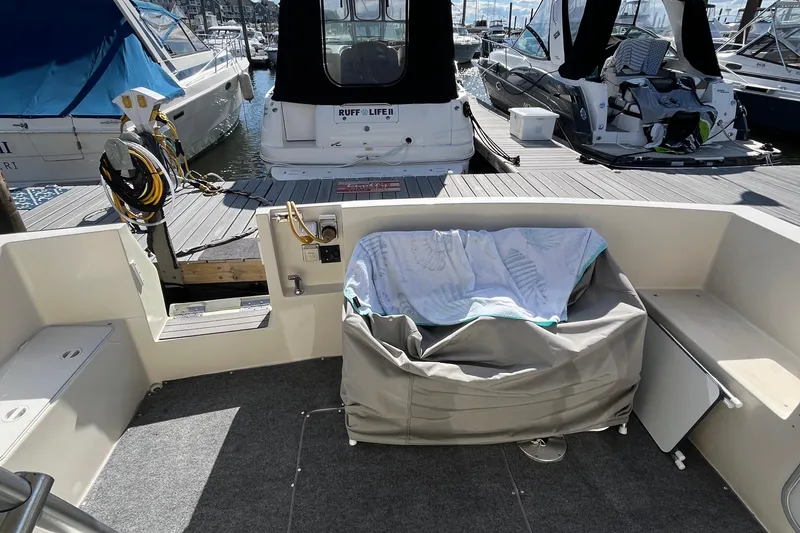 Slide: The Image of 1989 Mainship Mediterranean Convertible boat interior at marina, featuring seating and docked vessels. - 10