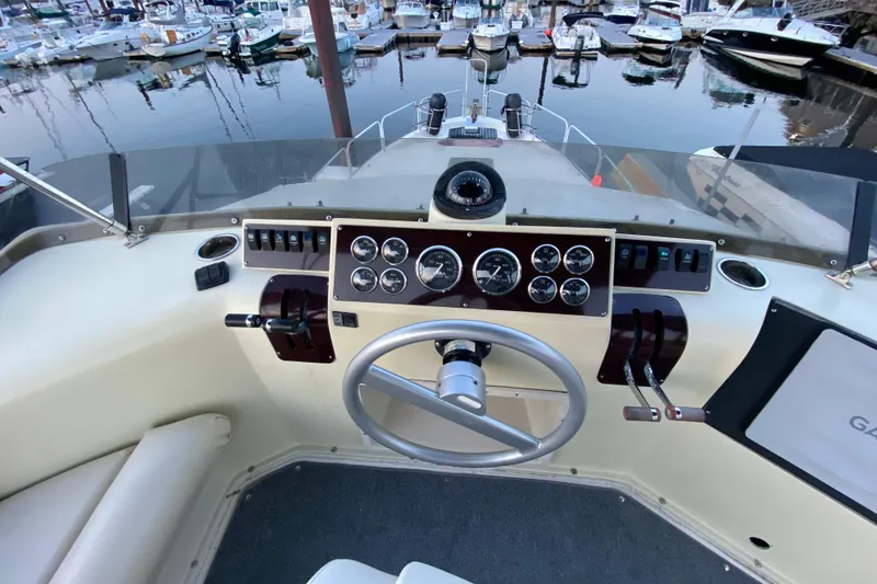 Slide: The Image of 1989 Mainship Mediterranean Convertible helm with gauges, steering wheel, and marina view. - 13