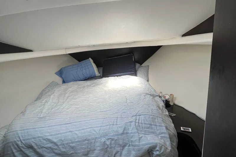 Slide: The Image of Cozy bedroom in 1989 Mainship Mediterranean Convertible boat with striped bedding and pillows. - 14