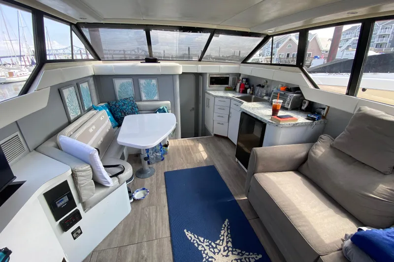 Slide: The Image of 1989 Mainship Mediterranean Convertible interior with modern seating, kitchenette, and nautical decor. - 18