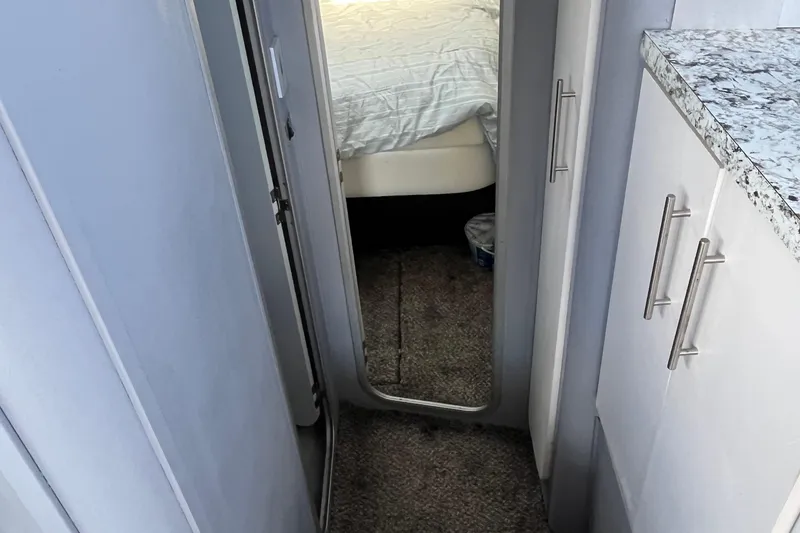 Slide: The Image of 1989 Mainship Mediterranean Convertible interior with bed, granite countertop, and white cabinetry. - 21