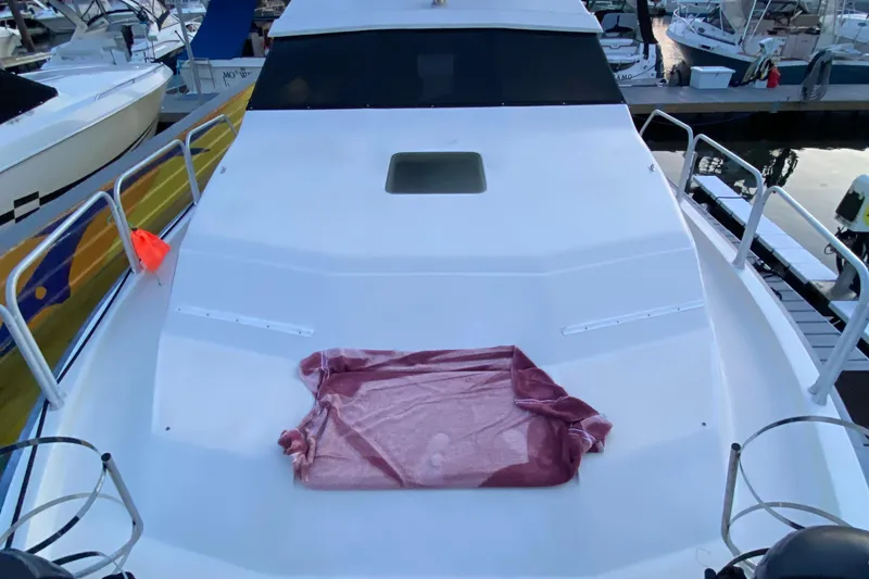 Slide: The Image of 1989 Mainship Mediterranean Convertible boat deck with a red towel, docked at marina. - 5