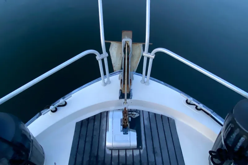 Slide: The Image of 1989 Mainship Mediterranean Convertible boat bow with anchor and railing, on calm water. - 6