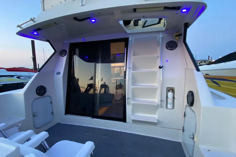 Slide: The Image of 1989 Mainship Mediterranean Convertible boat deck with blue lighting and sliding glass door. - 8