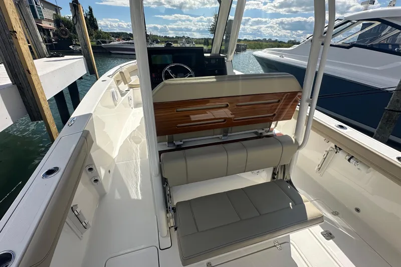 Slide: The Image of 2021 Pursuit S 288 Sport boat interior with seating and helm, docked by the water. - 15