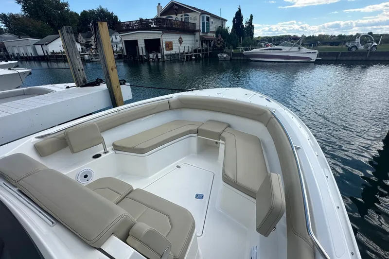 Slide: The Image of 2021 Pursuit S 288 Sport boat with beige seating, docked by waterfront homes. - 6