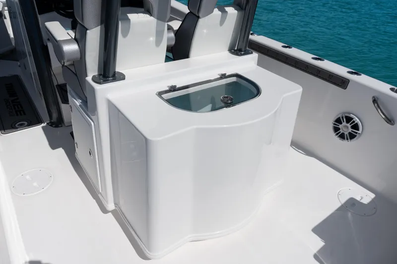 Slide: The Image of 2025 Twin Vee 260 GFX2 CC boat interior with seating and storage, on clear blue water. - 21