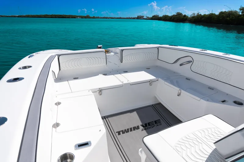 Slide: The Image of 2025 Twin Vee 260 GFX2 CC boat interior with white seating and turquoise water backdrop. - 26