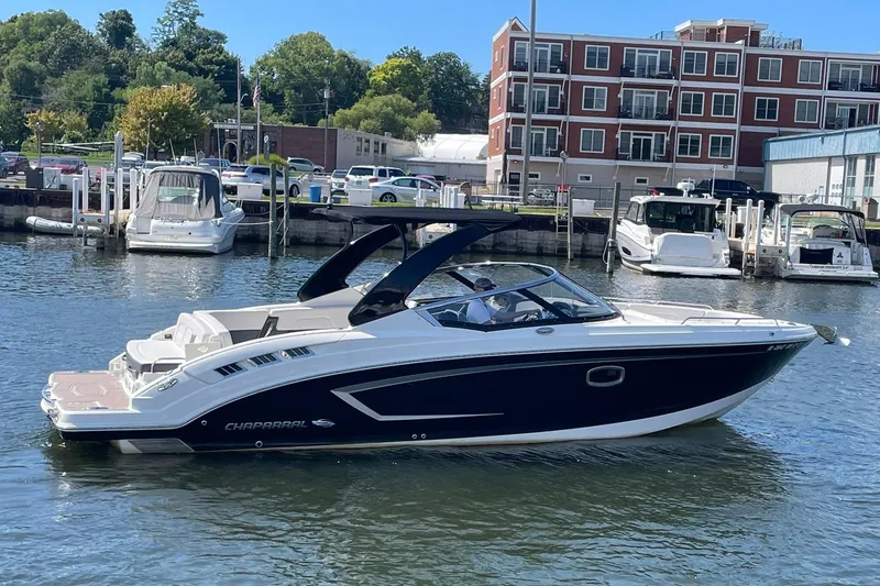 Slide: The Image of 2016 Chaparral 307 SSX boat docked in marina with modern buildings in background. - 1