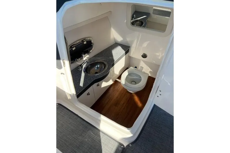 Slide: The Image of 2016 Chaparral 307 SSX boat interior with sink, toilet, and wood flooring. - 14