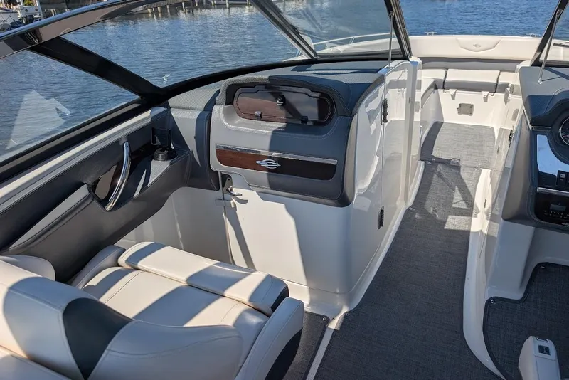 Slide: The Image of 2016 Chaparral 307 SSX boat interior with seating and dashboard, docked by the water. - 16