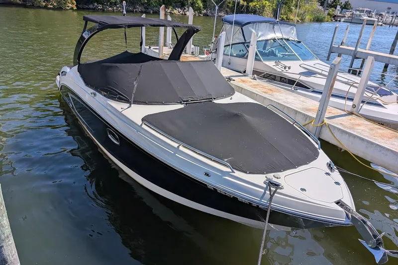 Slide: The Image of 2016 Chaparral 307 SSX boat docked with black covers, calm water background. - 2