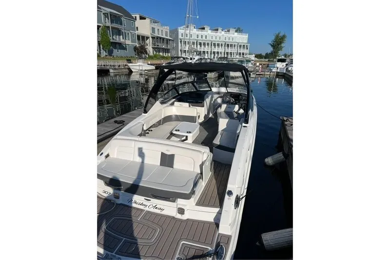 Slide: The Image of 2016 Chaparral 307 SSX boat docked at a marina with modern buildings. - 23
