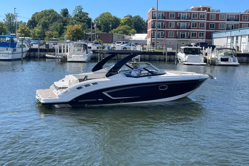 Slide: The Image of 2016 Chaparral 307 SSX boat docked in a marina with surrounding buildings and trees. - 27