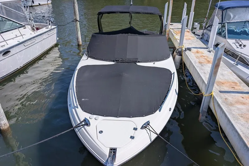 Slide: The Image of 2016 Chaparral 307 SSX boat docked with black cover, surrounded by water and other boats. - 3