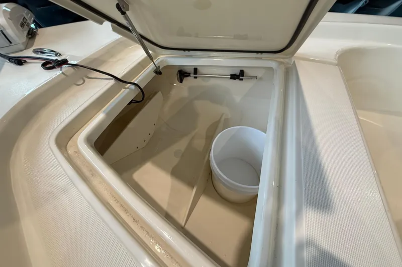 Slide: The Image of Open storage compartment in 2026 Scout 177 XSS boat with white bucket inside. - 5
