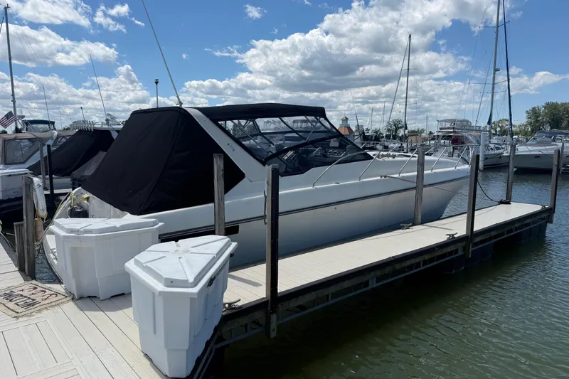 The Image of 1990 Silverton 34 Express boat docked at marina under blue sky. - 0