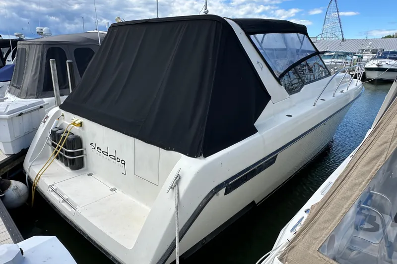 The Image of 1990 Silverton 34 Express boat docked with black canopy cover. - 1