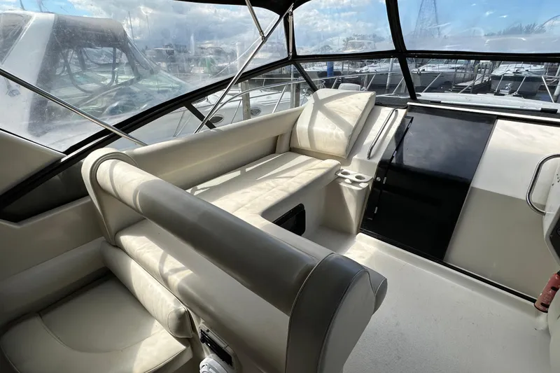 Slide: The Image of 1990 Silverton 34 Express boat interior with beige seating and large windows. - 14