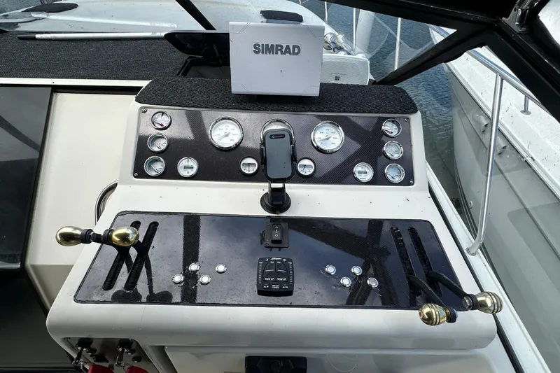 Slide: The Image of 1990 Silverton 34 Express boat dashboard with gauges and controls, featuring a Simrad device. - 23
