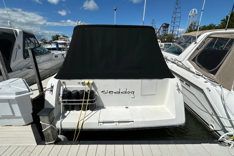 Slide: The Image of 1990 Silverton 34 Express boat docked, featuring a black cover and "sleddog" text on the stern. - 3