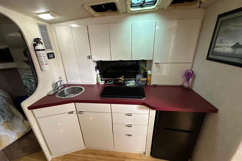 Slide: The Image of 1990 Silverton 34 Express yacht interior kitchen with red countertop, sink, and cabinets. - 31