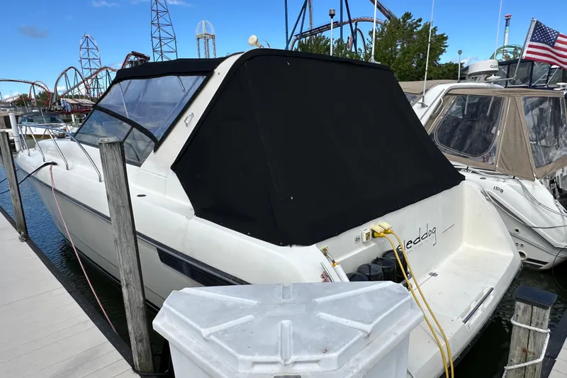 Slide: The Image of 1990 Silverton 34 Express boat docked, covered with black canvas, near amusement park rides. - 4