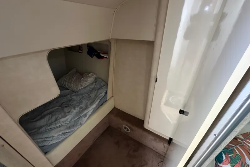 Slide: The Image of 1990 Silverton 34 Express cabin interior with cozy bed and storage. - 44