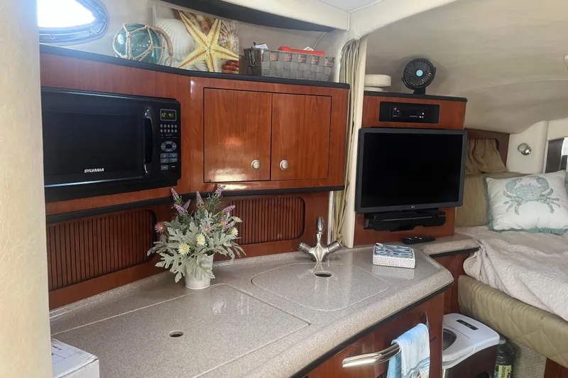Slide: The Image of 2007 Sea Ray 300 Sundancer cabin interior with kitchenette, TV, and cozy sleeping area. - 18
