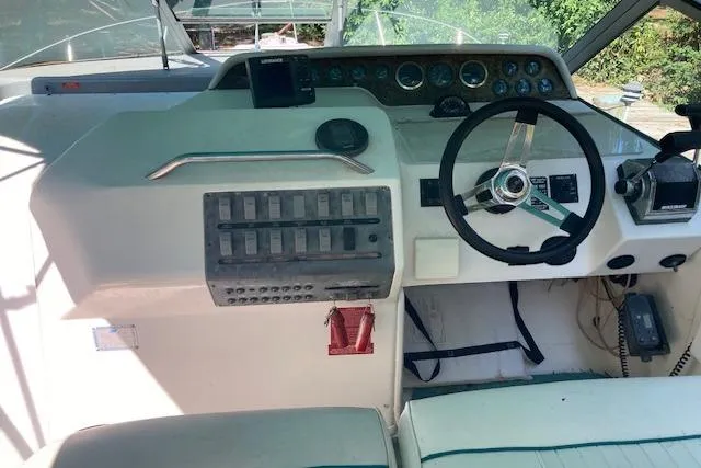 Slide: The Image of 1994 Sea Ray 290 Sundancer helm with steering wheel, control panel, and navigation instruments. - 9