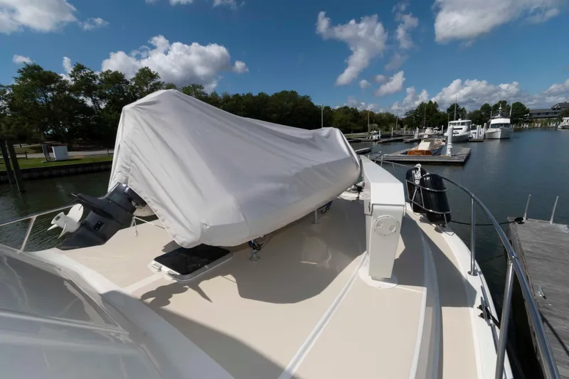 Slide: The Image of 1990 Viking 50 Motor Yacht deck with covered equipment, docked in a marina under blue skies. - 16