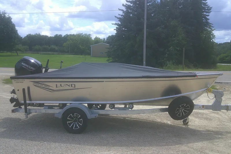 Slide: The Image of 2026 Lund 1800 Explorer Tiller boat on trailer, covered, with Mercury outboard motor. - 13