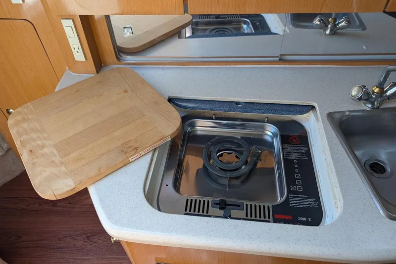 Slide: The Image of 2001 Regal Commodore 2660 boat kitchen with stove, cutting board, and sink. - 35
