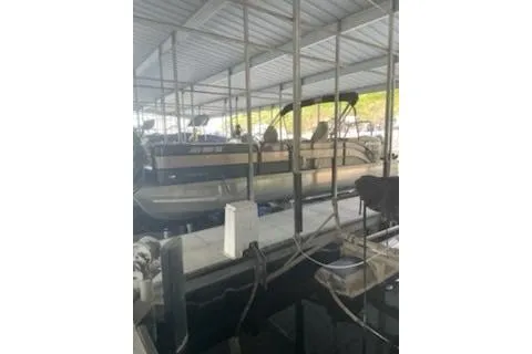 Slide: The Image of 2023 PlayCraft 27 Infinity pontoon boat docked in a covered marina. - 2