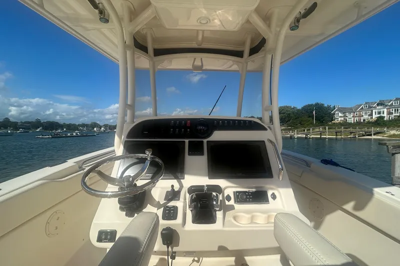 Slide: The Image of 2017 Grady-White Canyon 306 boat helm with steering wheel and controls, docked by waterfront homes. - 5
