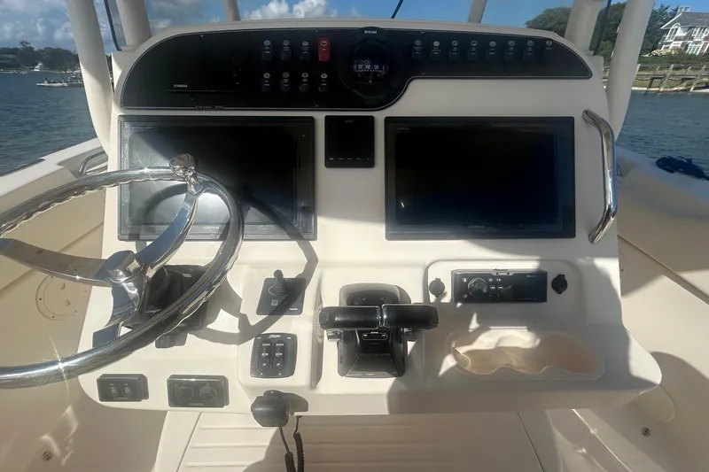 Slide: The Image of 2017 Grady-White Canyon 306 helm with dual displays and steering wheel, docked by the water. - 6