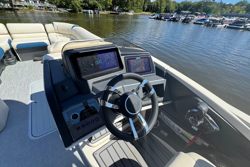 Slide: The Image of 2026 Tahoe Pontoon Grand Tahoe LTD Quad Lounge helm with modern controls on a lake. - 9
