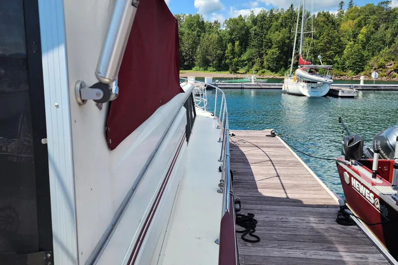 Slide: The Image of 1989 Marinette 32 Sedan Flybridge docked at a scenic marina with lush greenery. - 11
