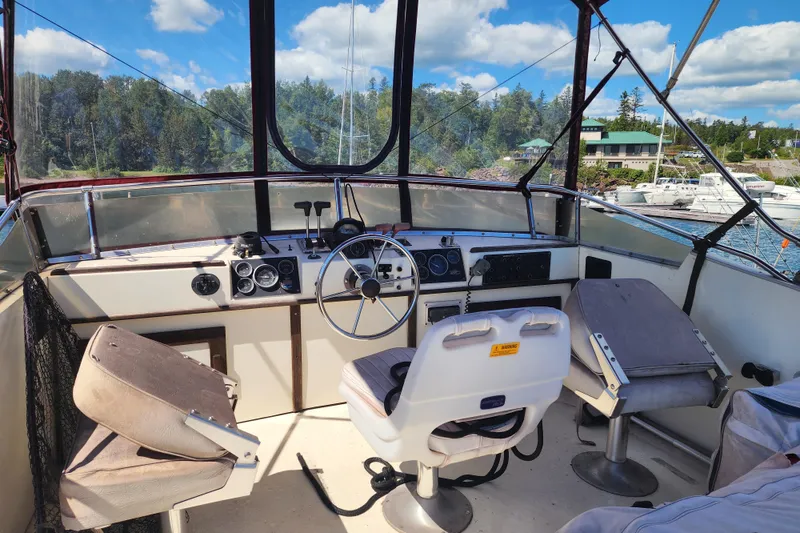 Slide: The Image of 1989 Marinette 32 Sedan Flybridge interior with steering wheel, controls, and seating, docked by a marina. - 12