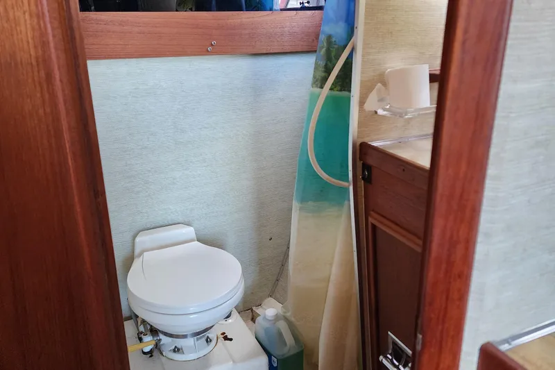 Slide: The Image of 1989 Marinette 32 Sedan Flybridge bathroom with toilet, shower curtain, and wooden cabinetry. - 18