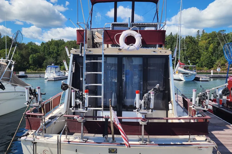 Slide: The Image of 1989 Marinette 32 Sedan Flybridge docked, featuring fishing equipment and scenic marina backdrop. - 3