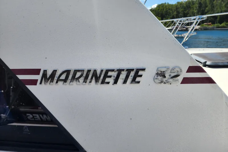 Slide: The Image of 1989 Marinette 32 Sedan Flybridge boat nameplate with maroon stripes, docked by water. - 4