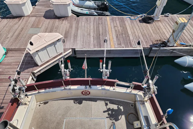 Slide: The Image of 1989 Marinette 32 Sedan Flybridge at dock with fishing rod holders and American flag. - 9