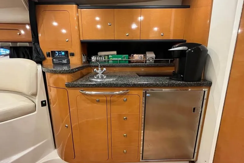 Slide: The Image of 2008 Chaparral 330 Signature yacht interior with kitchenette, featuring wood cabinets and modern appliances. - 9