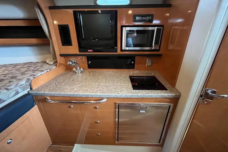 Slide: The Image of 2009 Chaparral Signature 280 interior kitchen with sink, stove, microwave, and compact fridge. - 9