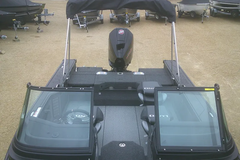 Slide: The Image of 2025 Lund 1875 Pro-V boat with open cockpit and covered engine, parked on gravel. - 4