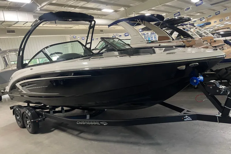 The Image of 2026 Chaparral 23 SSi boat on trailer in showroom, sleek design, black and white exterior. - 0